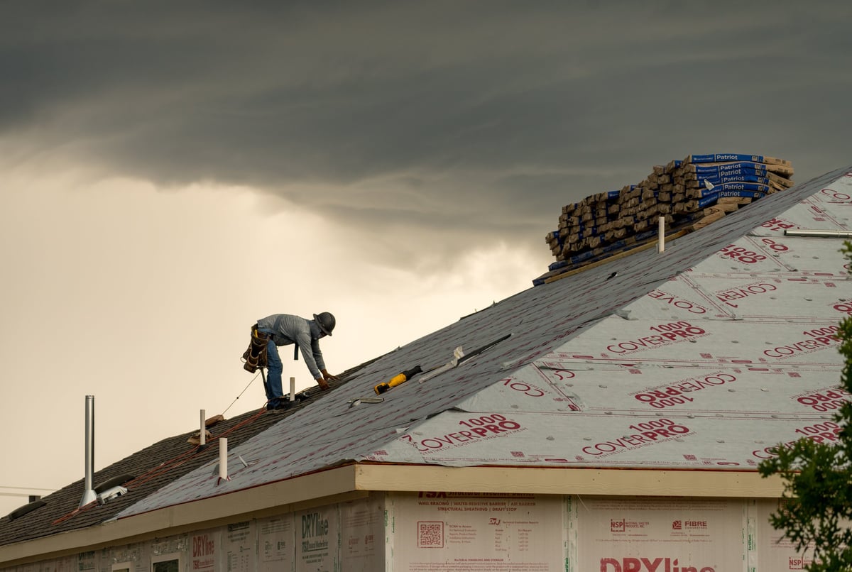 Roofer working on a home roof during stormy weather